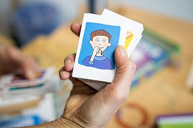 Eine Hand hält eine Karte mit dem Symbol in DGS für "essen"