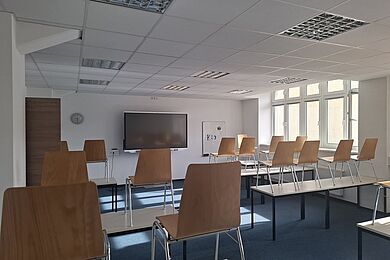 Leerer Klassenraum, moderne digitale Tafel, braune Stühle