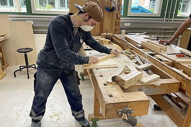 Im Fachbereich Holztechnik schleift ein Teilnehmer Holz.